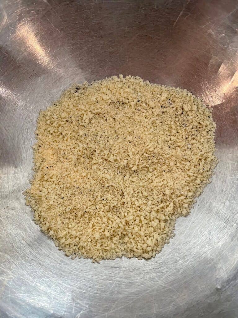 Bread crumbs, garlic powder, salt and pepper combined in a large mixing bowl for pesto turkey meatballs with ricotta cheese.