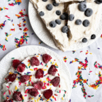 Greek Yogurt Breakfast Bark displayed on white parchment paper and bright white plates. The photo is decorated with rainbow sprinkles.