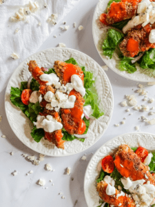 Three plates of pretzel crusted buffalo chicken tender salad.