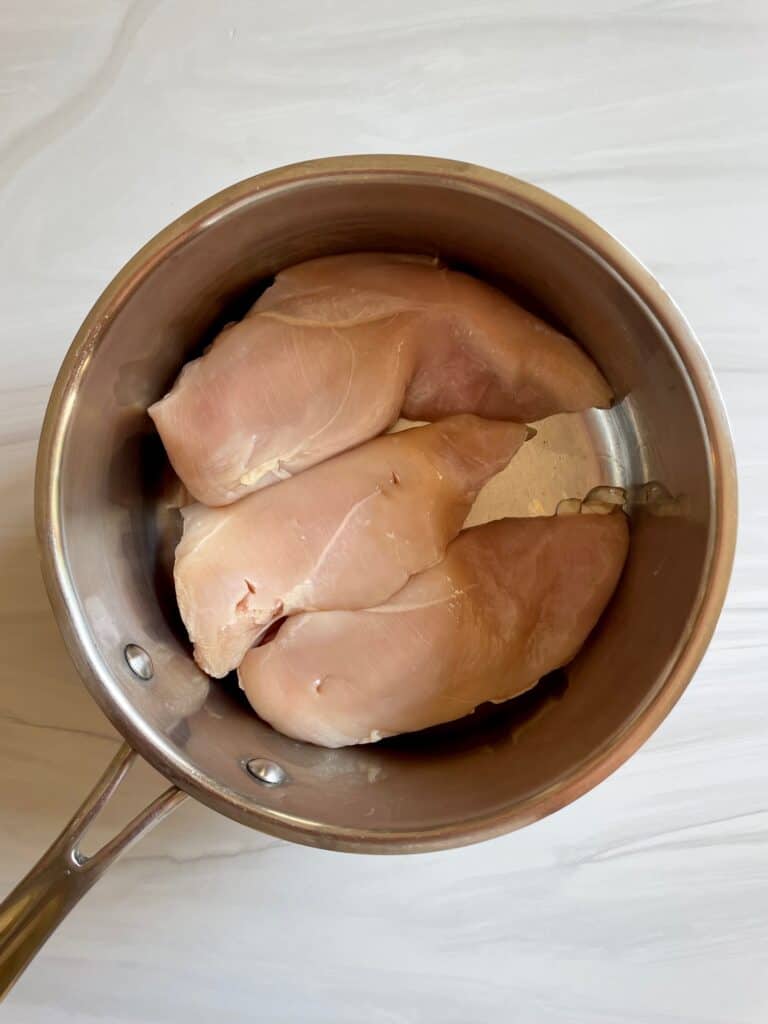Raw chicken breast in a saucepan.