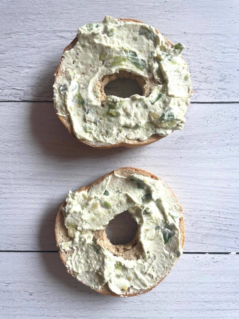 Bagel with avocado cream cheese spread on it.