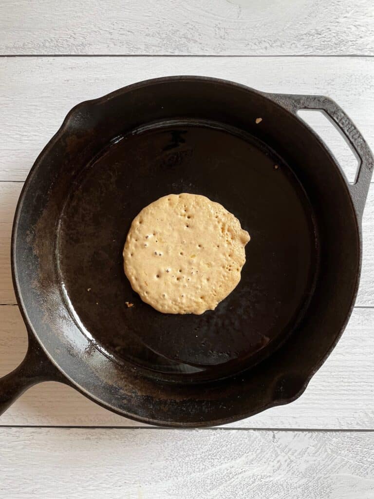 Pancake in a cast iron skillet ready to flip.