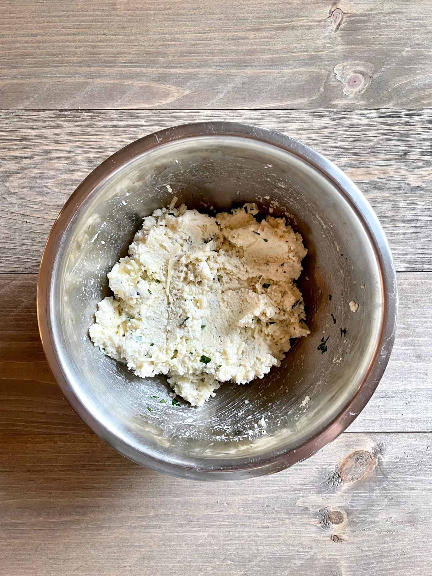 Ricotta cheese mixture in a stainless steel mixing bowl.