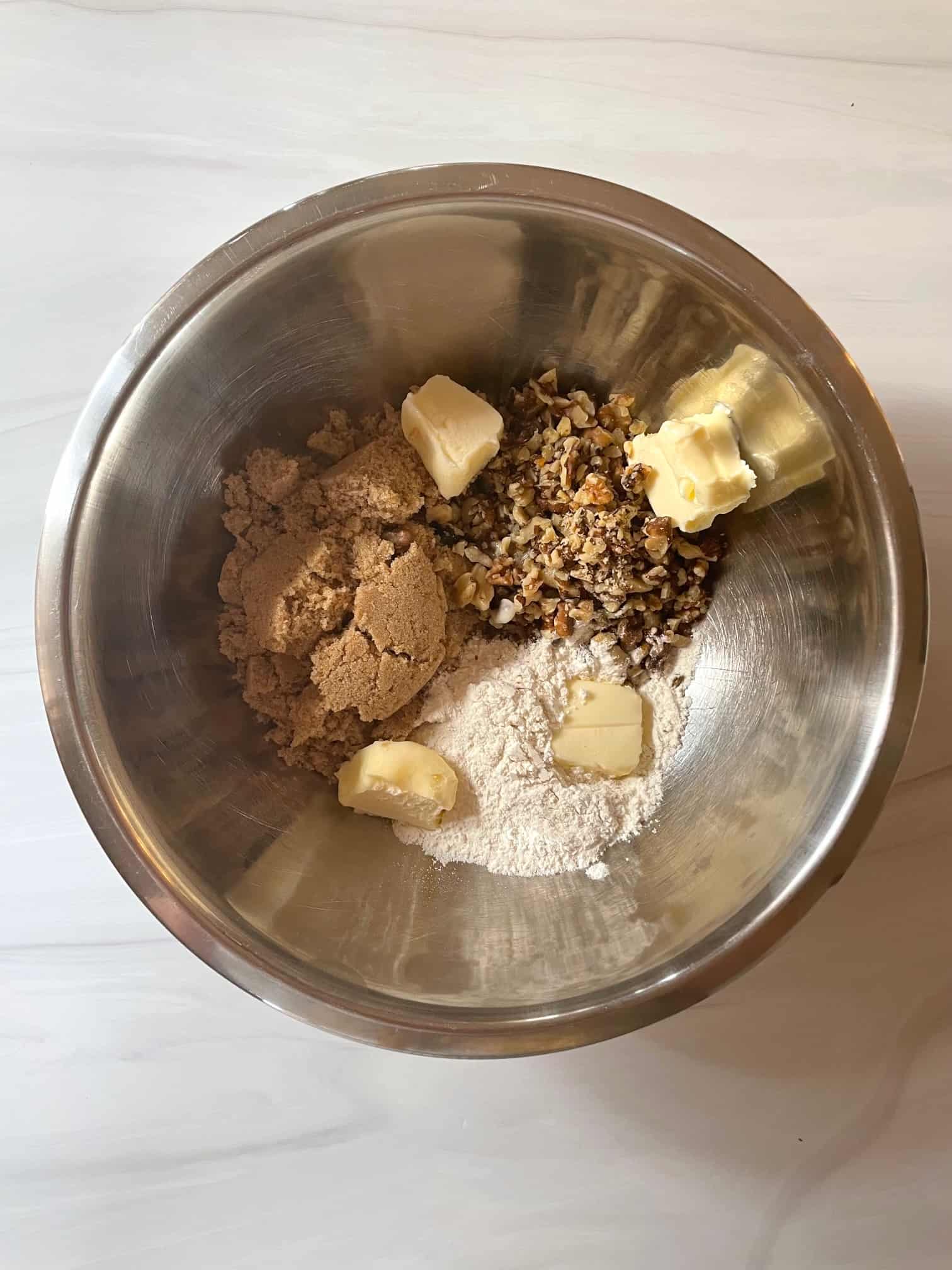 Brown sugar, walnuts, butter and flour in a stainless steel bowl