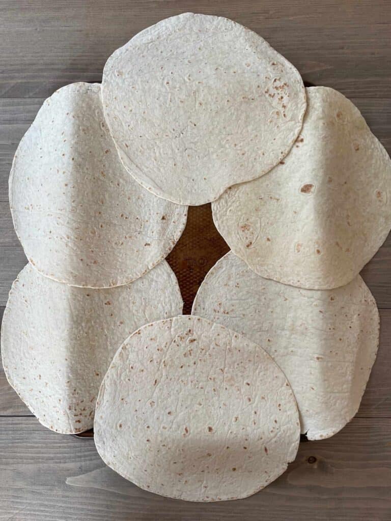 6 large tortilla shells layered on a sheet pan.