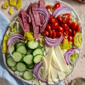 Grinder Salad on a large plate with a light blue napkin and various ingredients scattered around.