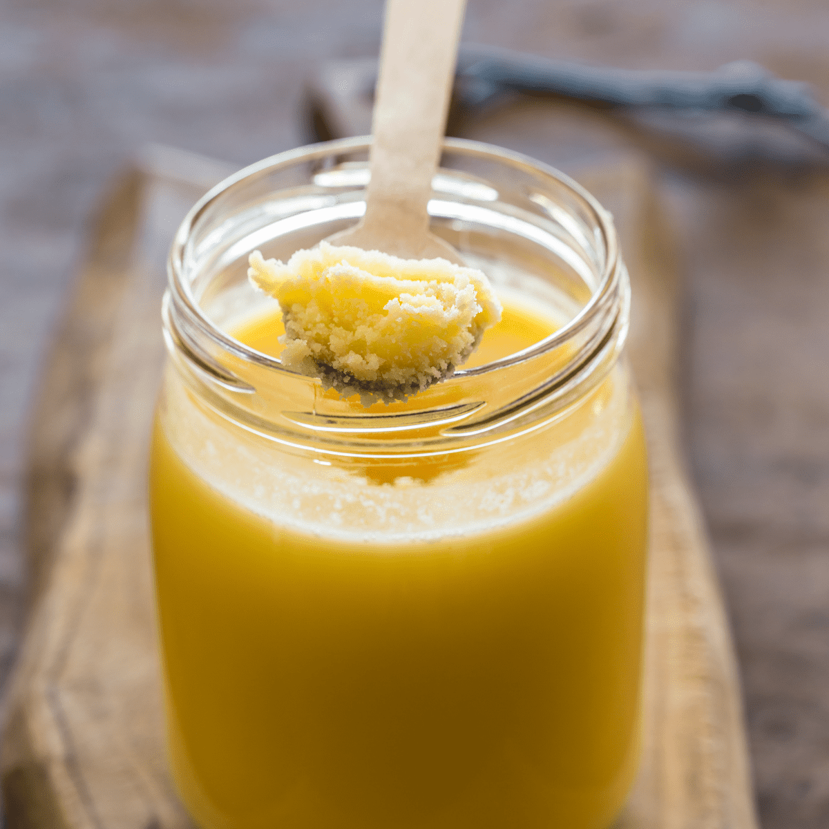 Ghee in a small glass jar with a wooden spoon.