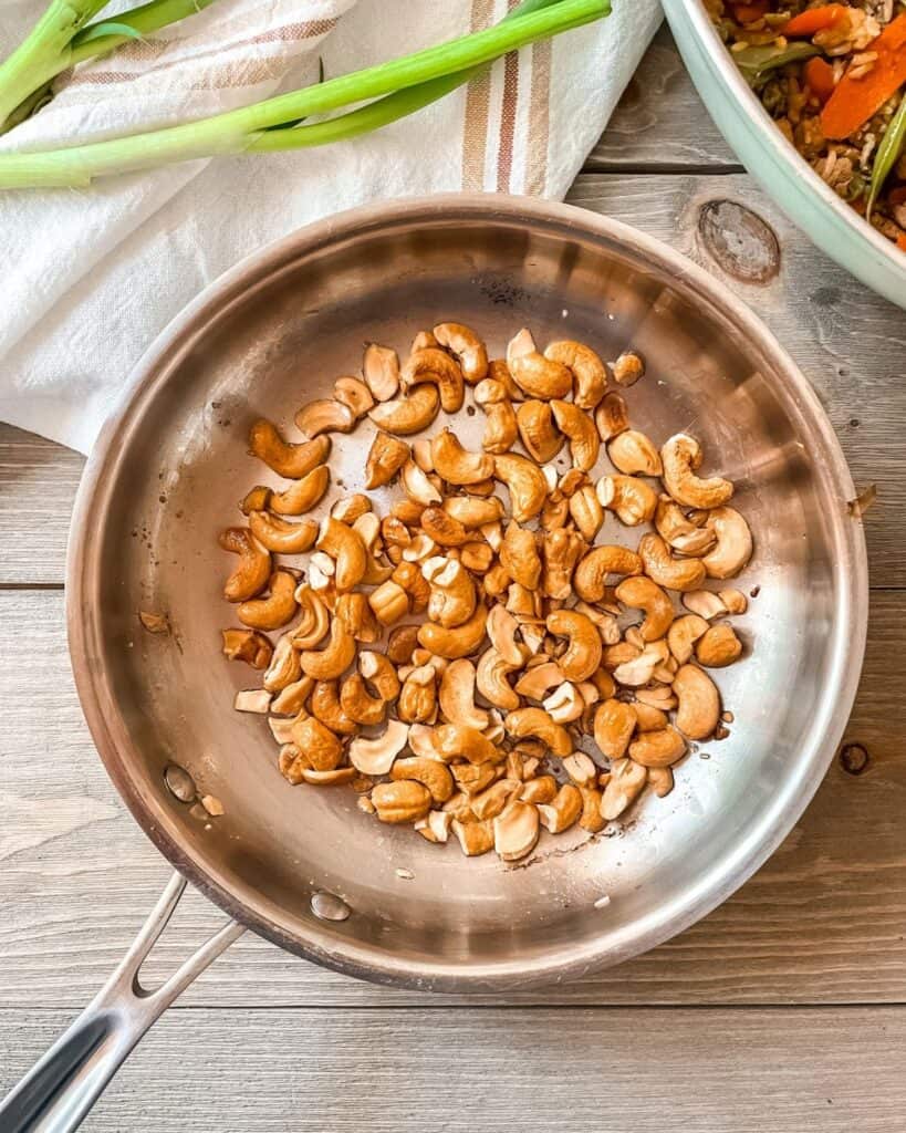 Chopped cashews in a small frying pan.