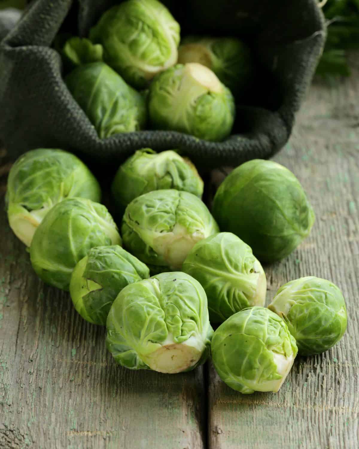 Fresh brussels sprouts in a green burlap bag, used as a substitute for asparagus.