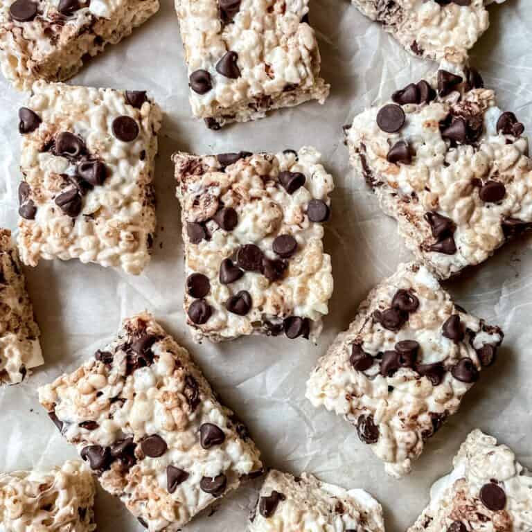 Rice krispies treats with chocolate chips cut into squares on parchment paper.