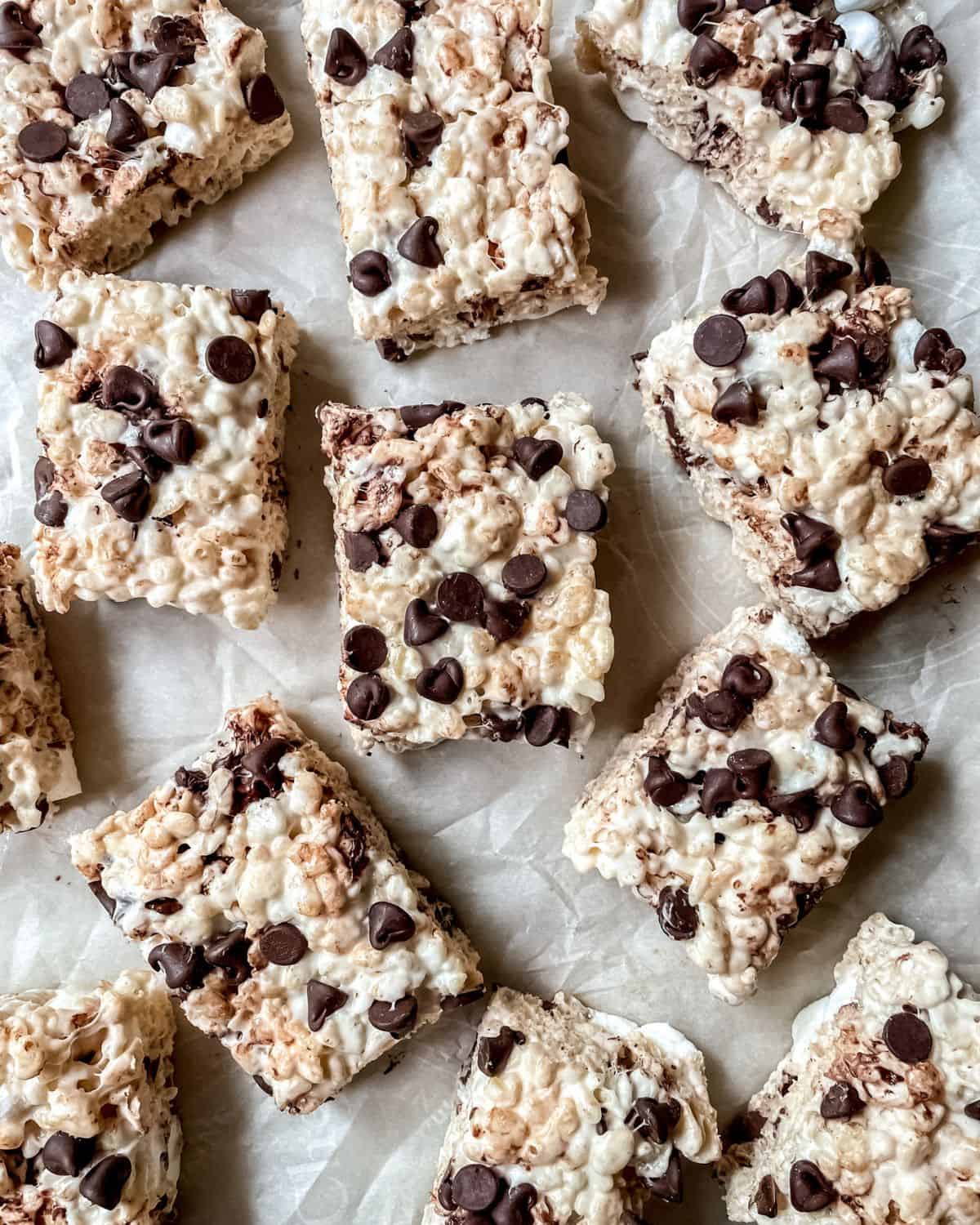 Rice krispies treats with chocolate chips cut into squares on parchment paper.