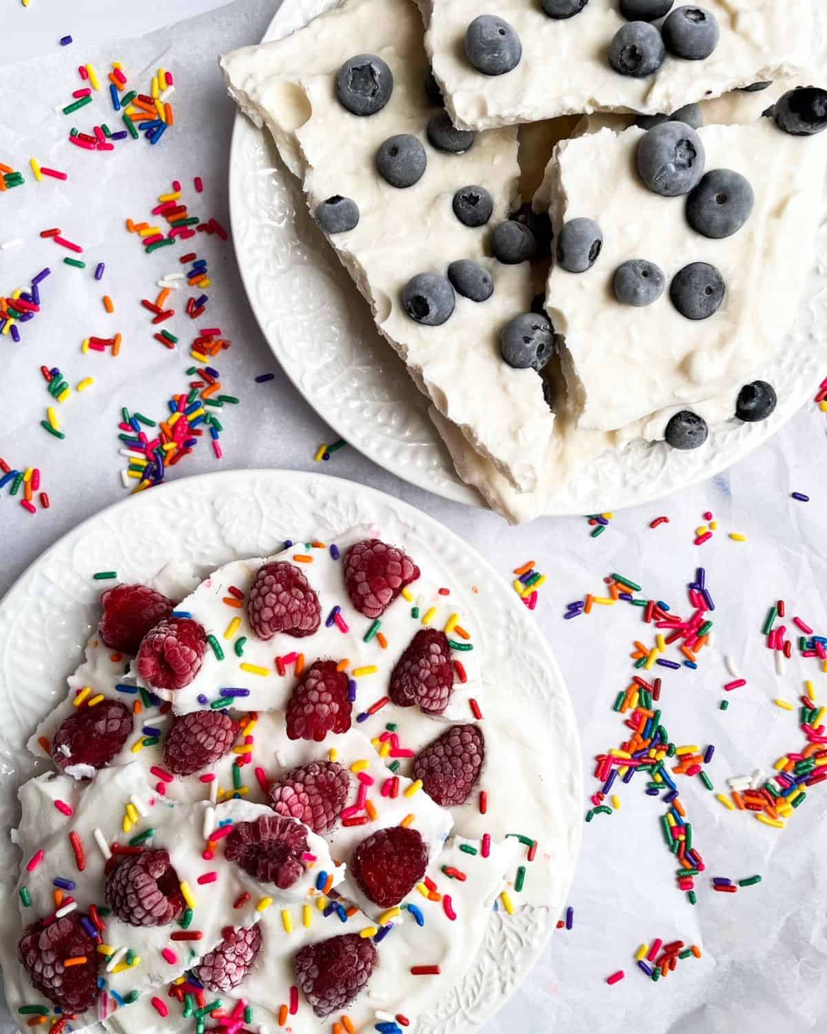 Breakfast bark on white plates with rainbow sprinkles on the table.