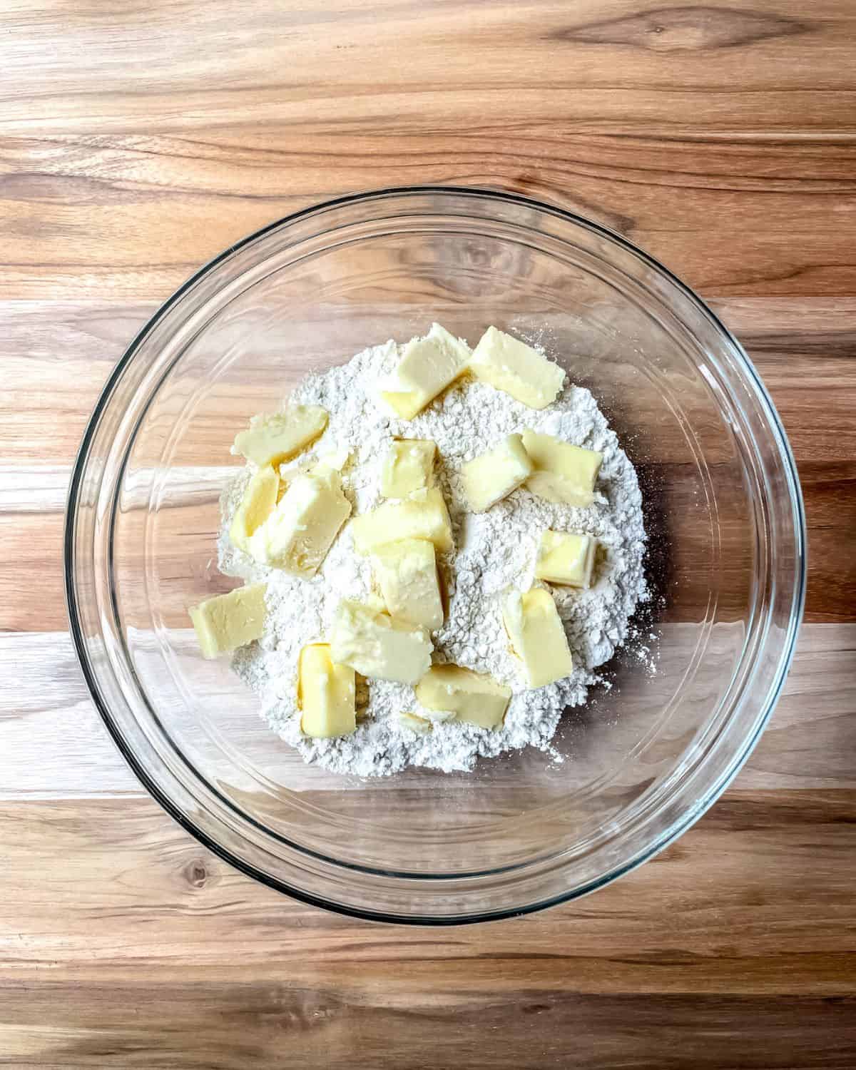 Flour with chunks of butter in a glass bowl.