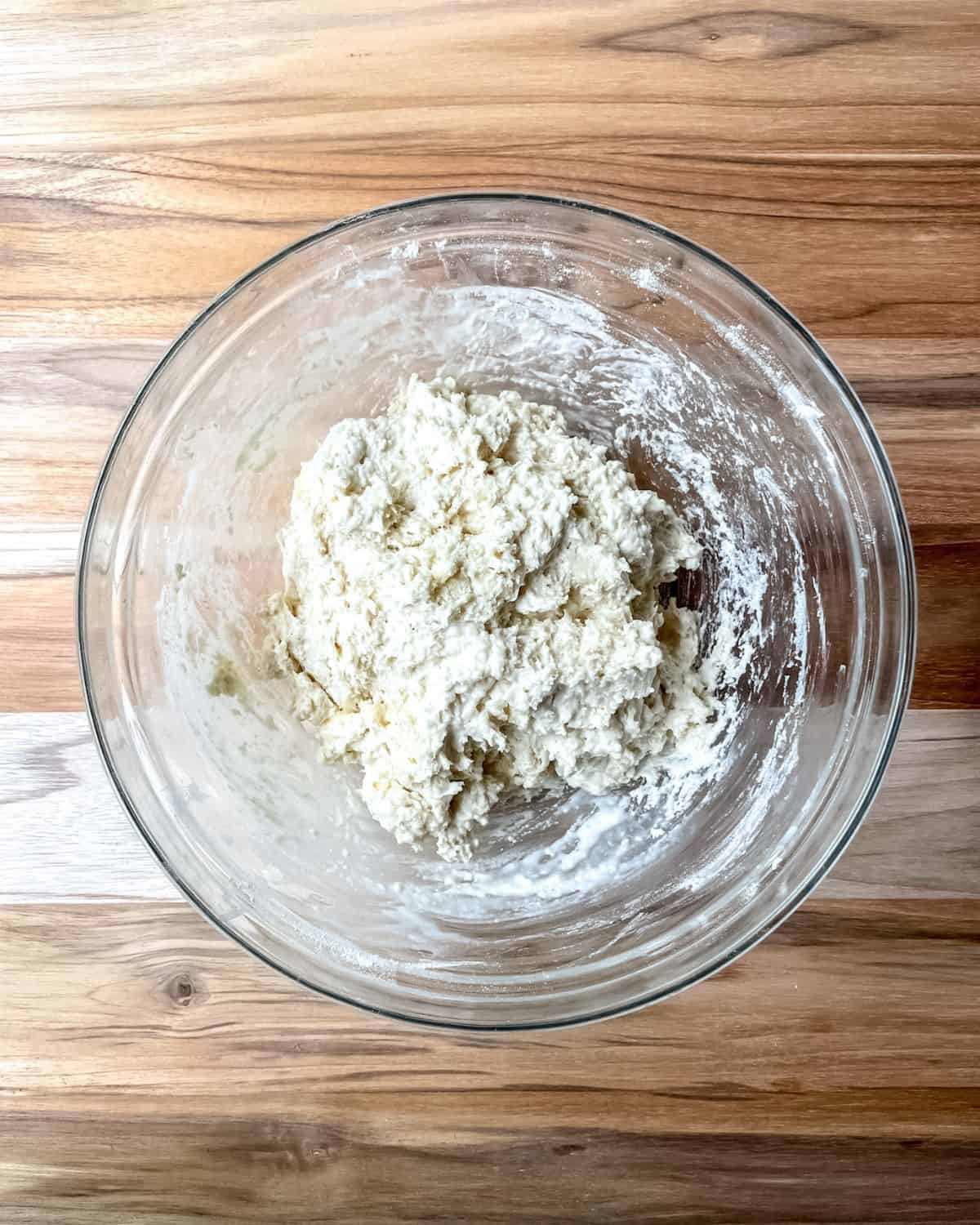 Flour, butter and milk mixed into a ball of dough in a glass bowl.