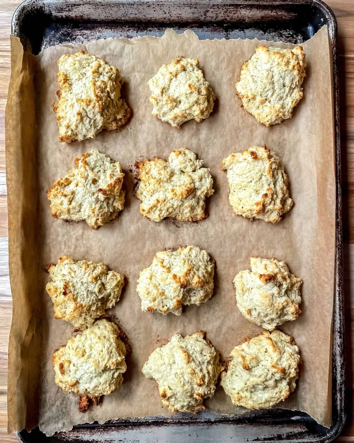 Baked 3 ingredient drop biscuits on a parchment lined baking sheet.
