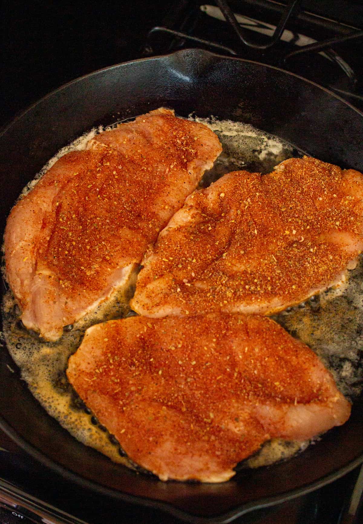 Chicken that is still raw and seasoned, just added to a hot skillet.