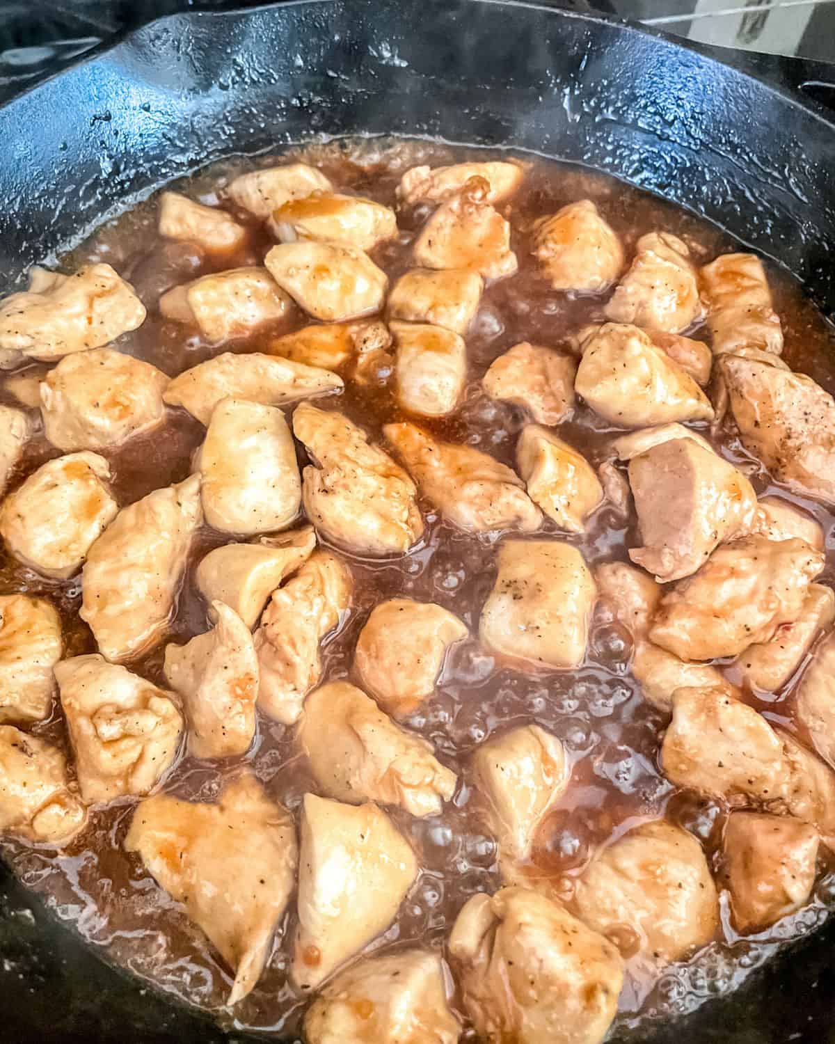 Cooked honey garlic chicken in a cast iron skillet with sauce.