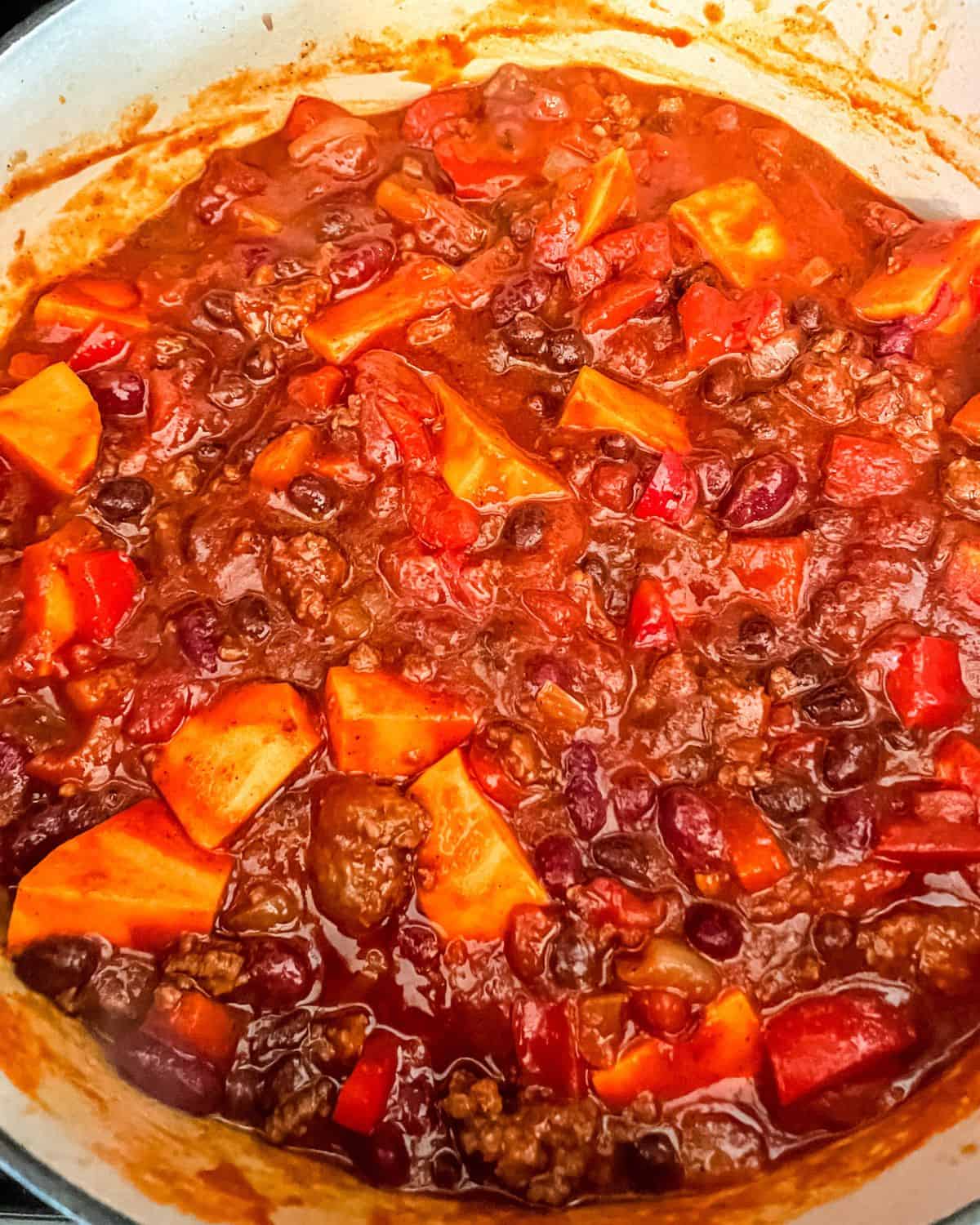 Tomato sauce, diced tomatoes, chopped sweet potatoes and beef broth added into the pot.