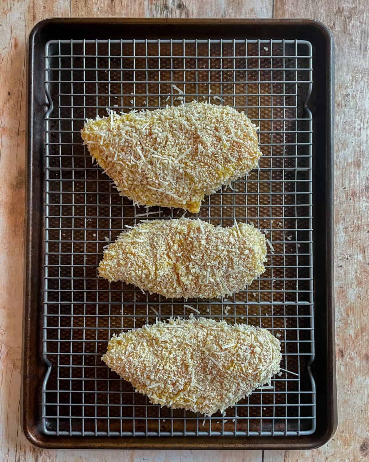 Panko crusted chicken breast on a sheet pan, ready to be baked.