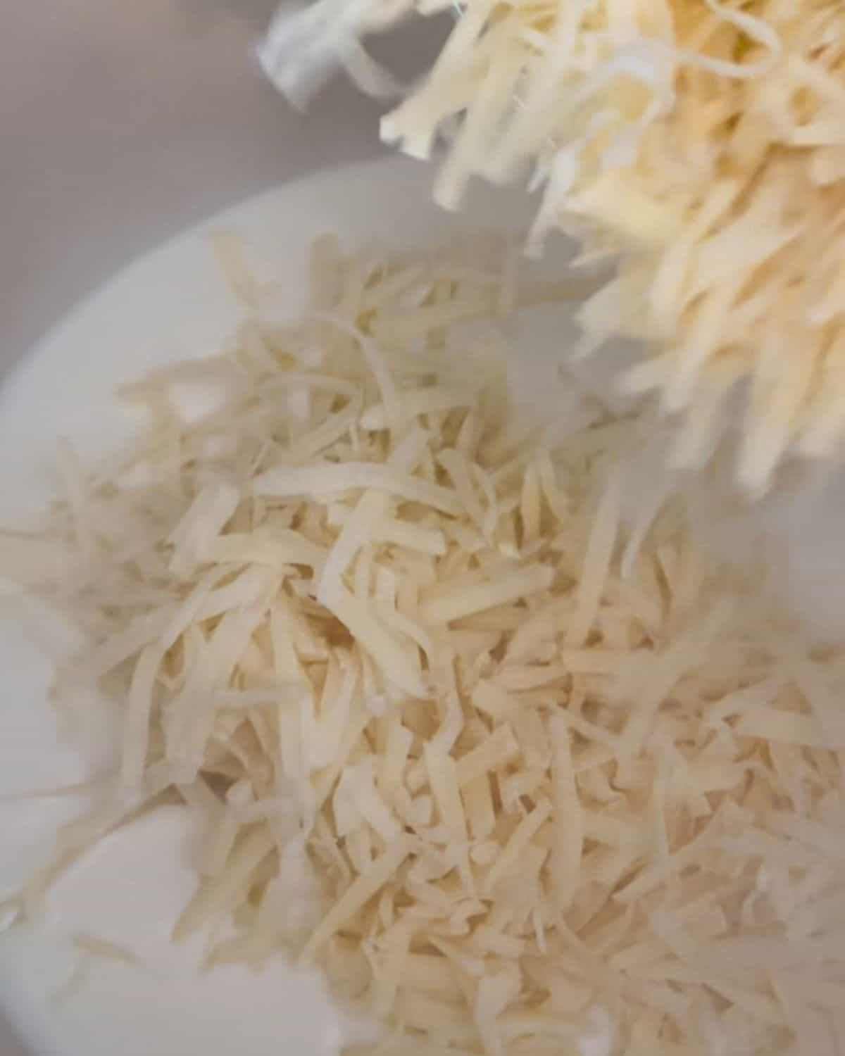 Shredded cheese being added to roux.