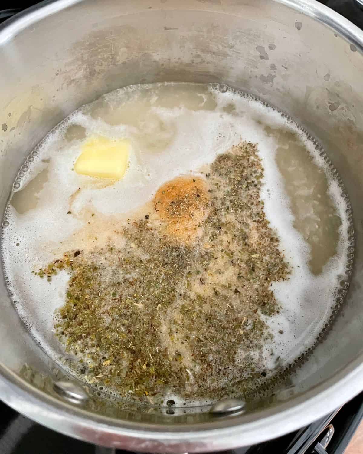 Chicken stock, rice, seasonings, and butter in a saucepan.