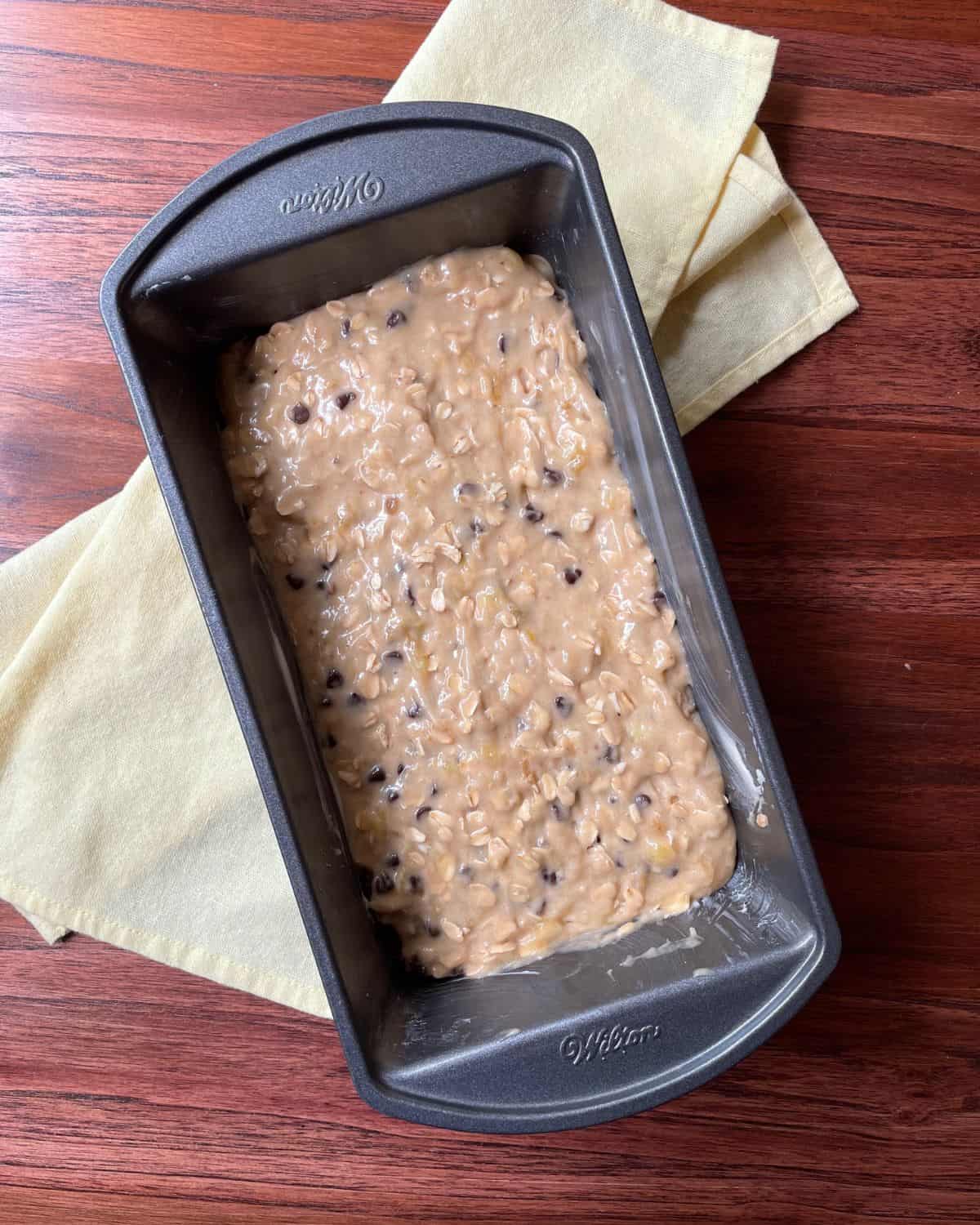 The batter for the Oatmeal Chocolate Chip Banana Bread is poured into a loaf pan.