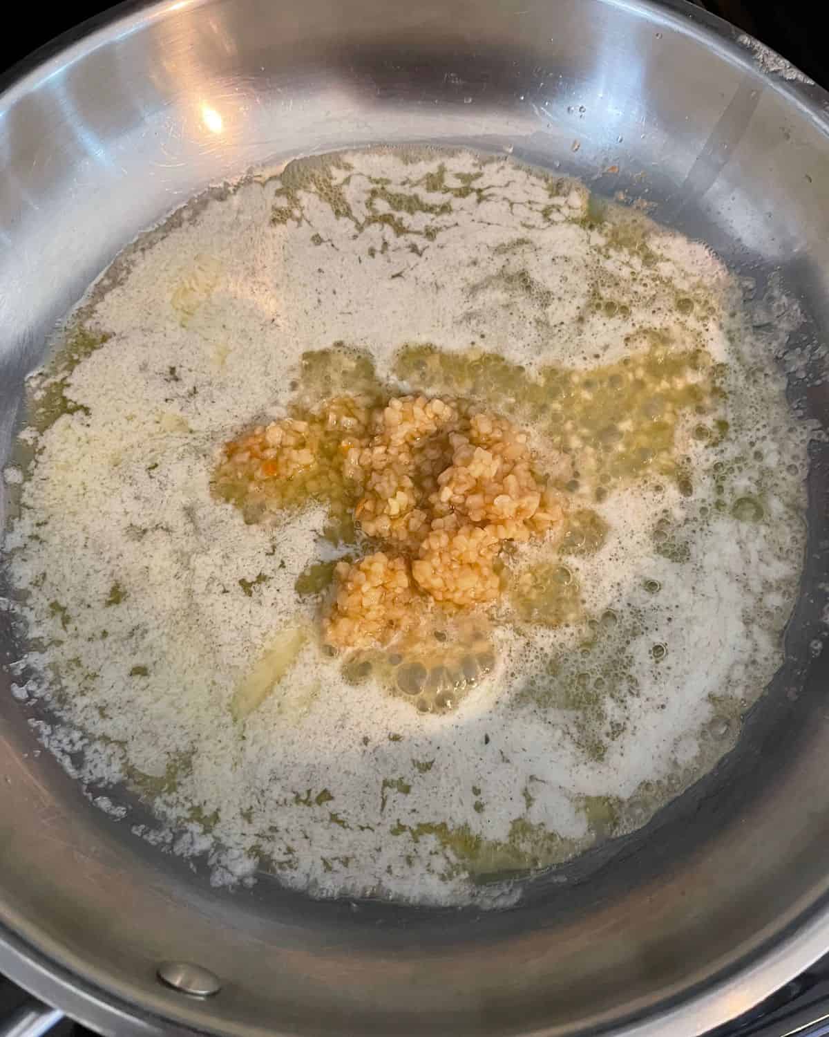 Minced garlic added to oil in a skillet.