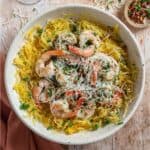 Grilled spaghetti squash shrimp scampi topped with parmesan cheese and red pepper flakes, in a bowl.