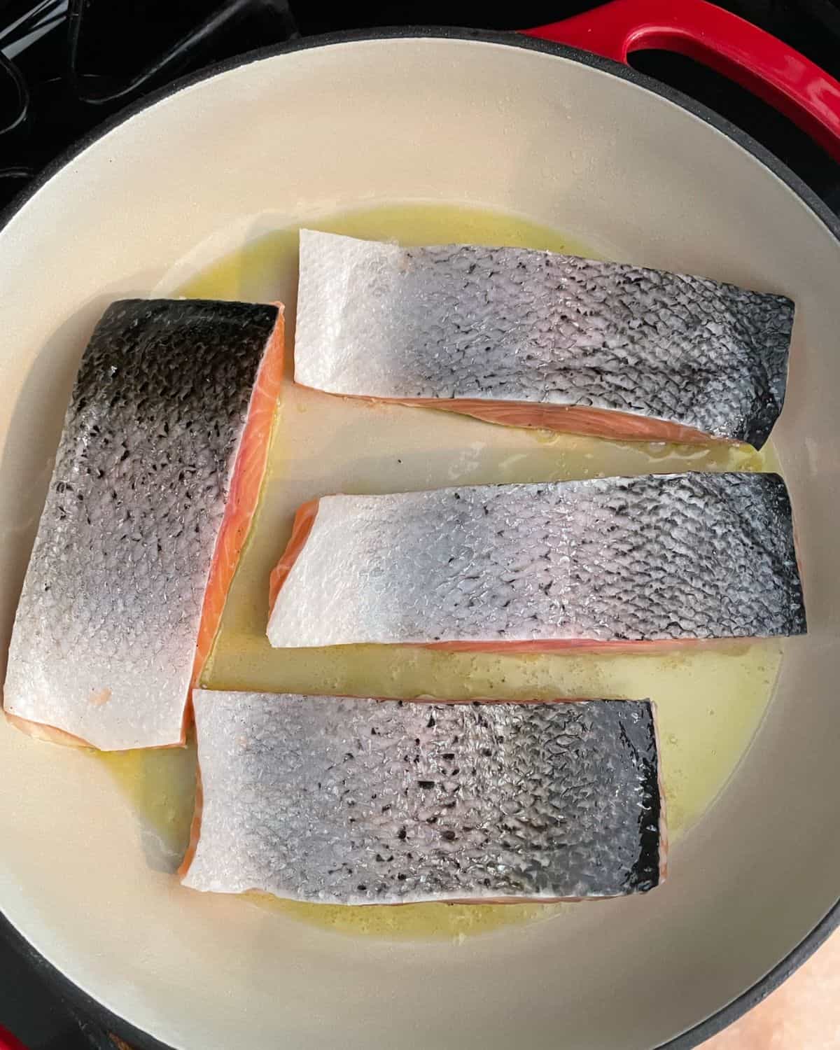 Fresh salmon searing in a pan, skin side up.