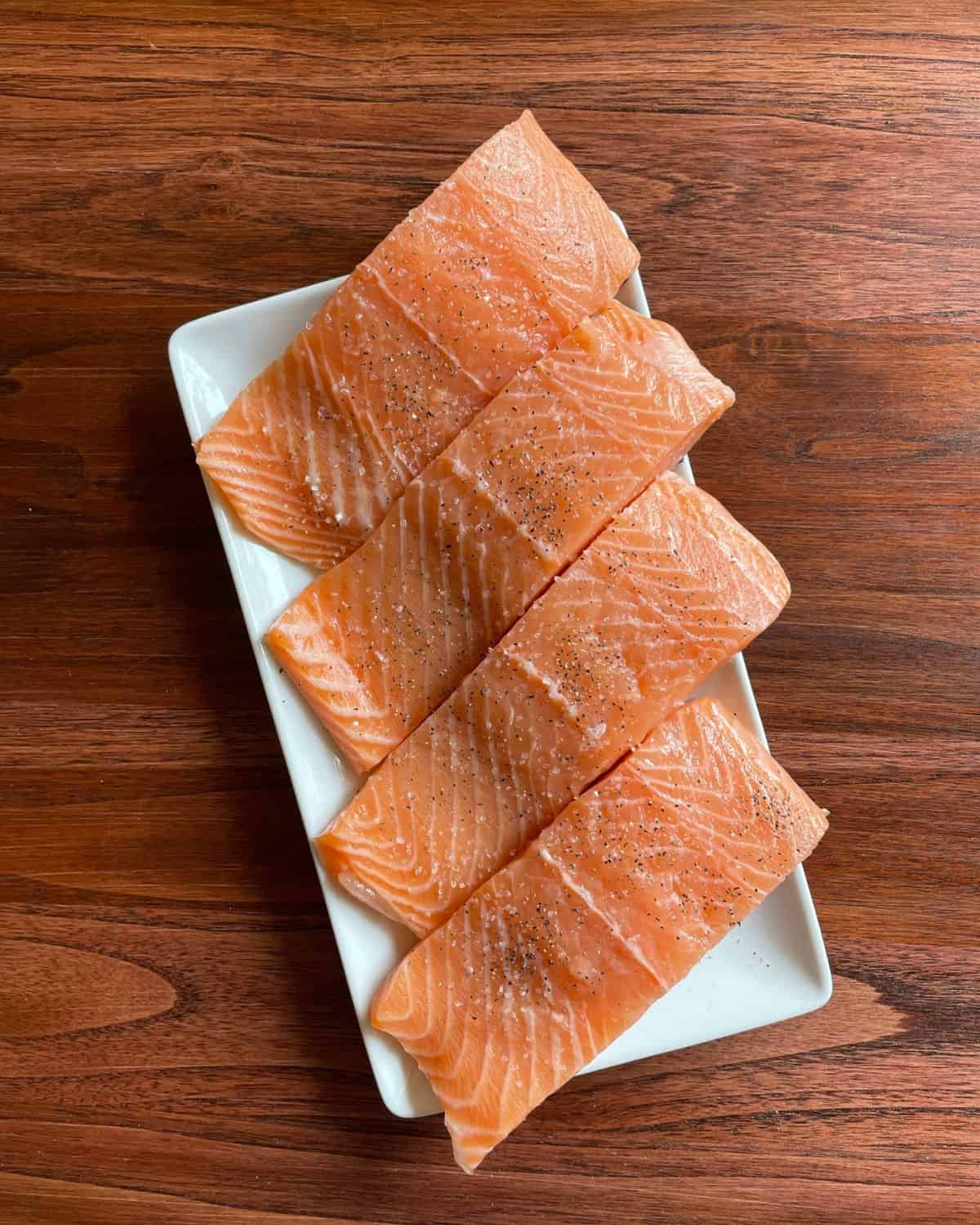 Seasoned fresh salmon filets on a plate.