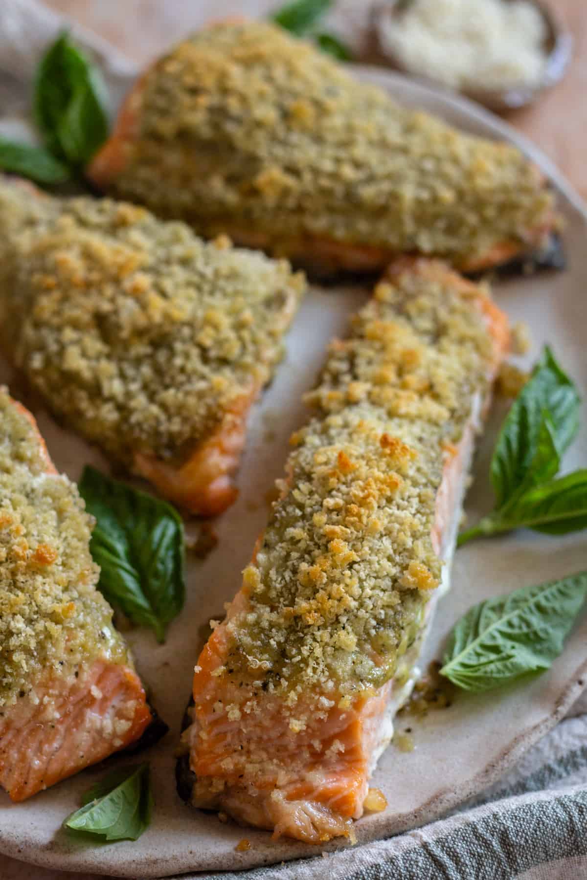 Easy baked pesto crusted salmon filets on a plate, garnished with fresh basil.
