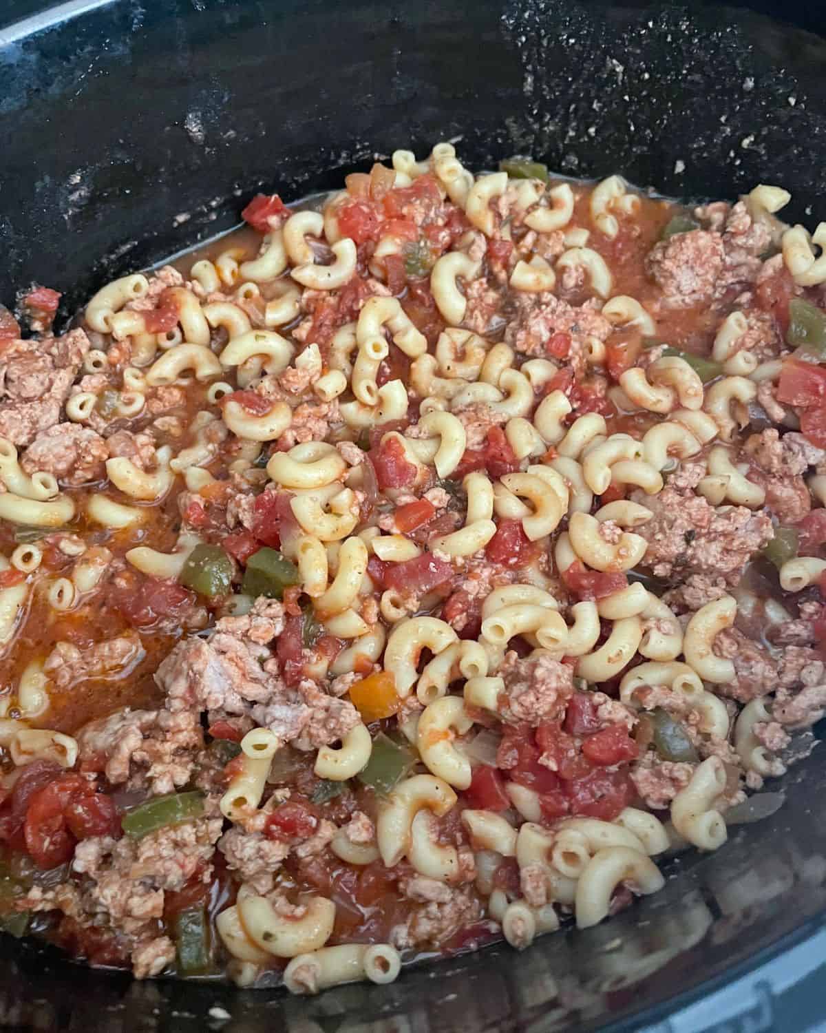 Goulash mixed in crock pot with cooked macaroni noodles.