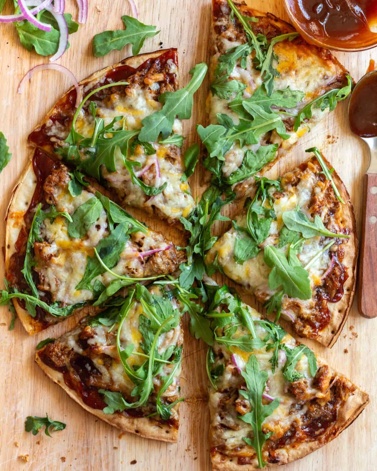 Pulled pork pizza with bbq sauce on a cutting board.