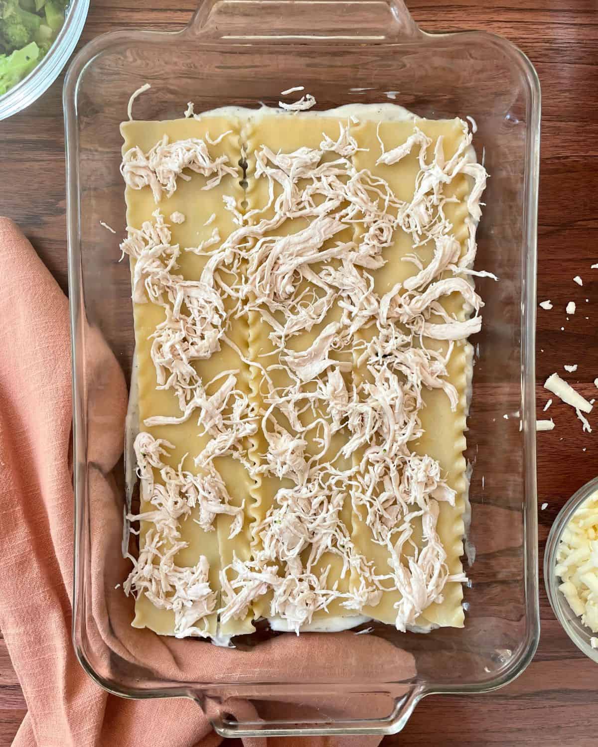 Shredded chicken sprinkled onto the lasagna noodles.