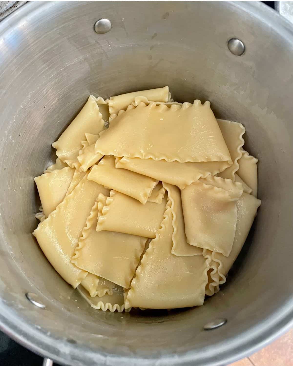 Cooked lasagna noodles in the bottom of a large stock pot.