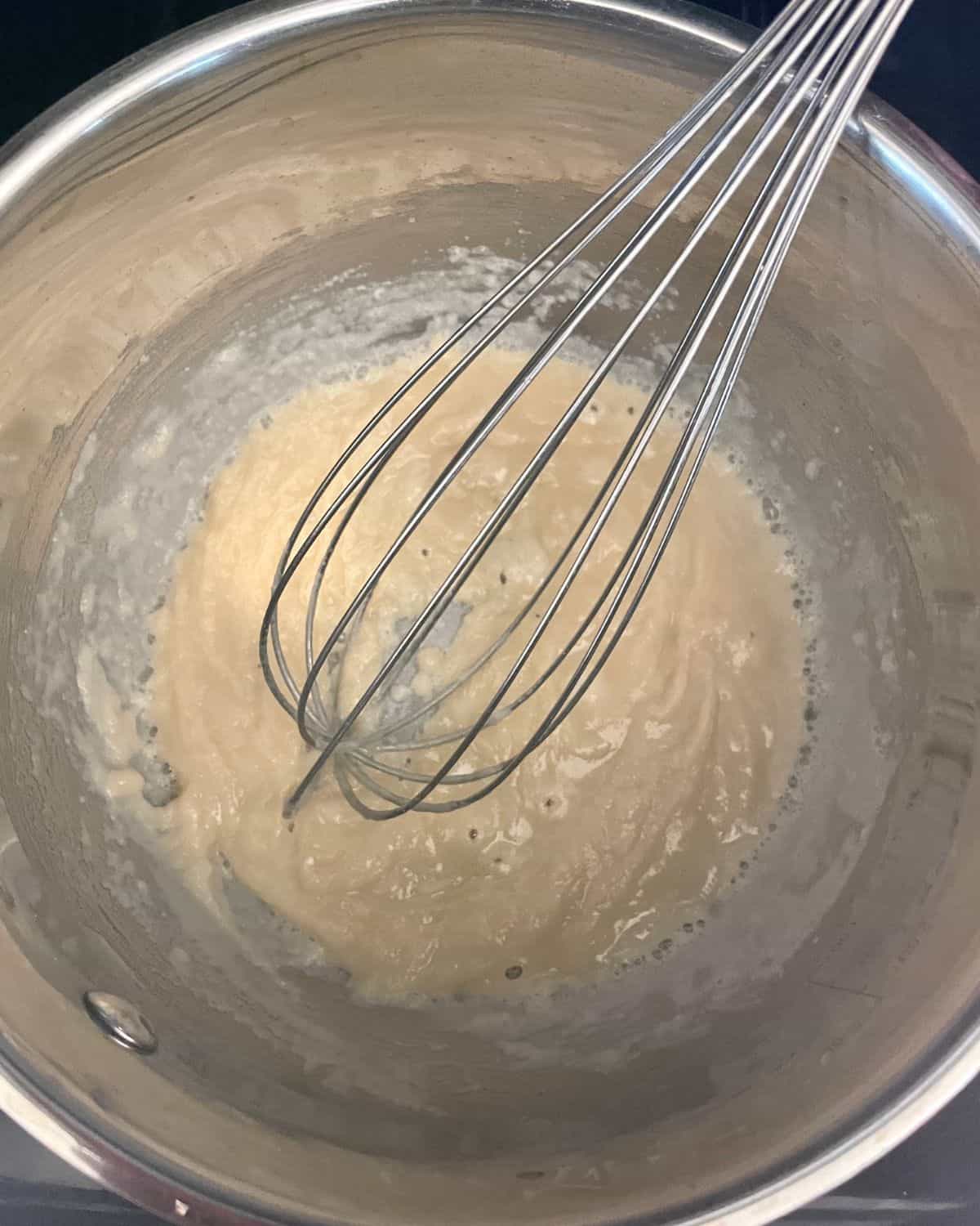 Flour added to the butter to form a roux, in a saucepan with a whisk.