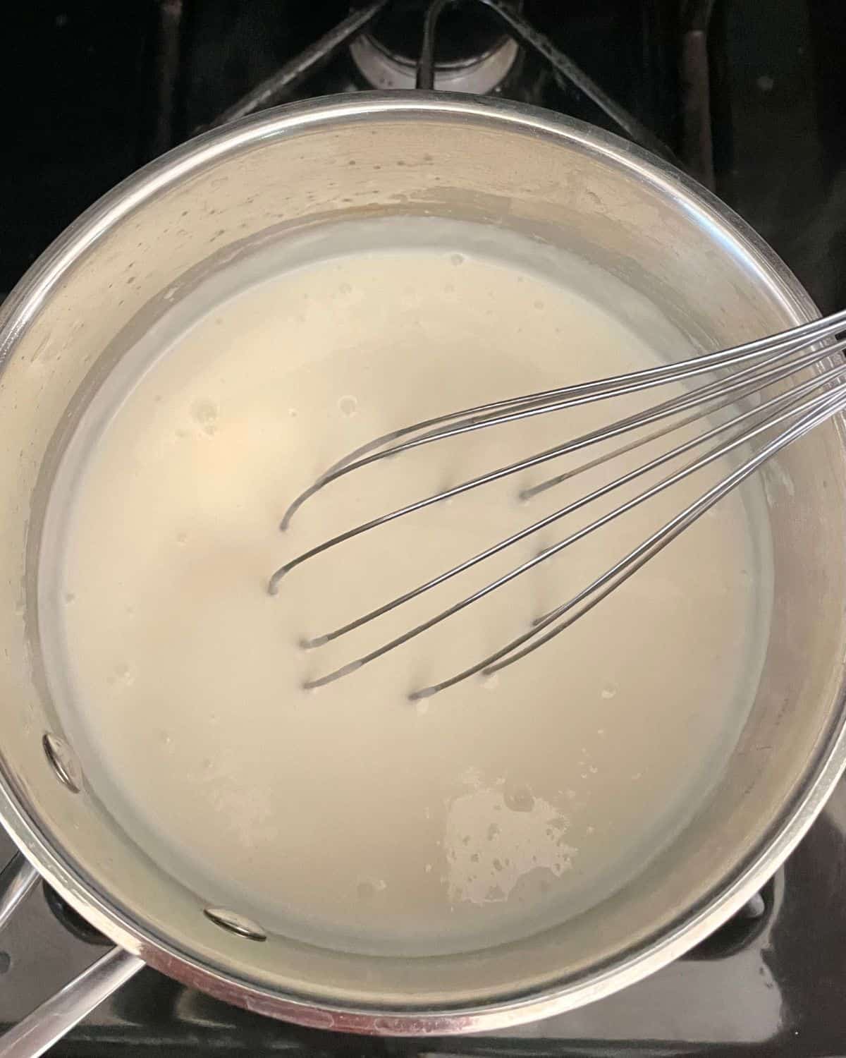 Milk added to the roux with a whisk.