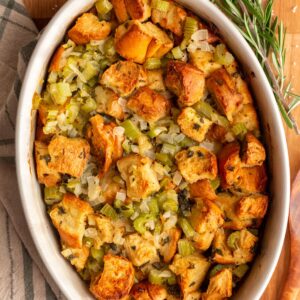 Brioche stuffing in a round casserole dish, garnished with fresh rosemary.