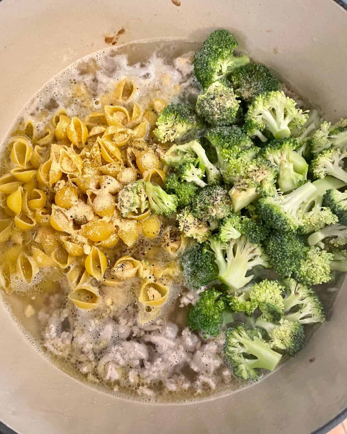 Broccoli and dry pasta noodles are added to the chicken stock and turkey.