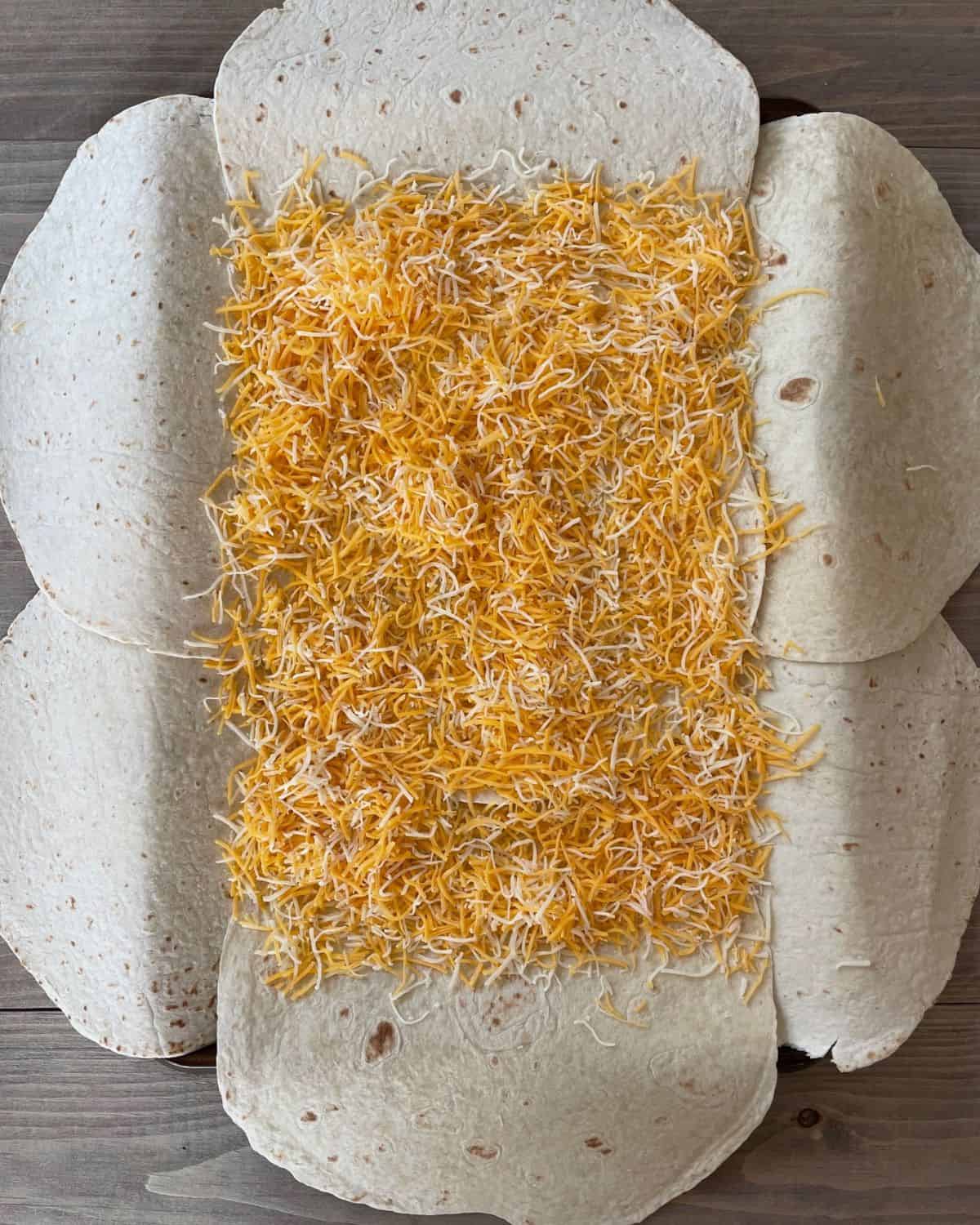 Shredded Mexican blend cheese layered onto the tortilla shells.