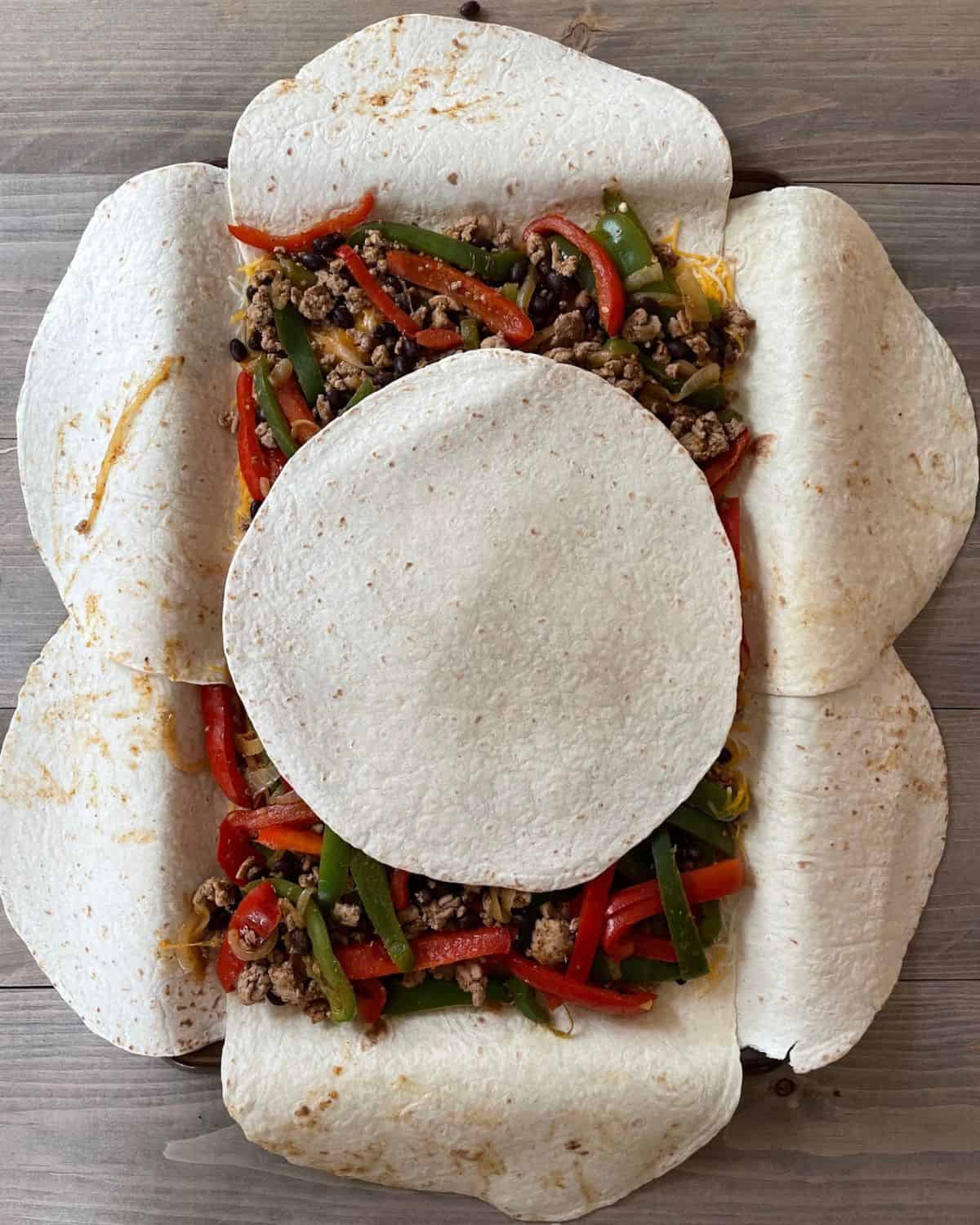 A single tortilla is placed on top of the ground turkey quesadilla mixture.