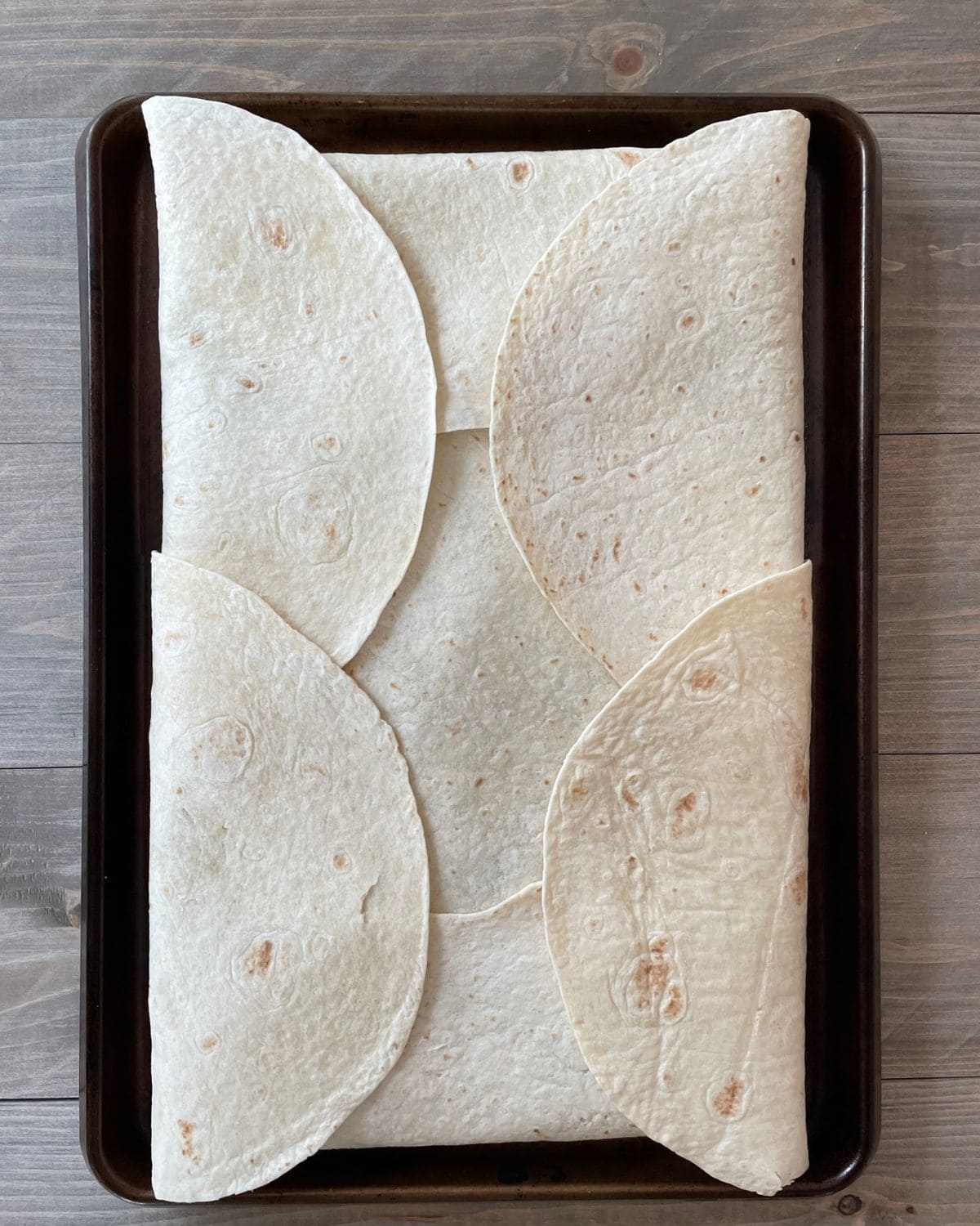 The overhanging edges of the tortillas are folded over on top of the quesadilla.