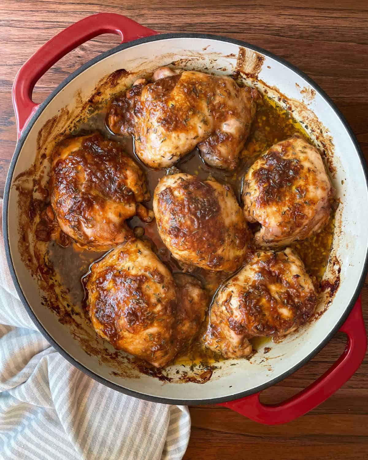 Balsamic chicken thighs fresh out of the oven, in a red baking dish.