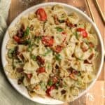Pesto pasta salad with sundried tomatoes in a large serving bowl.