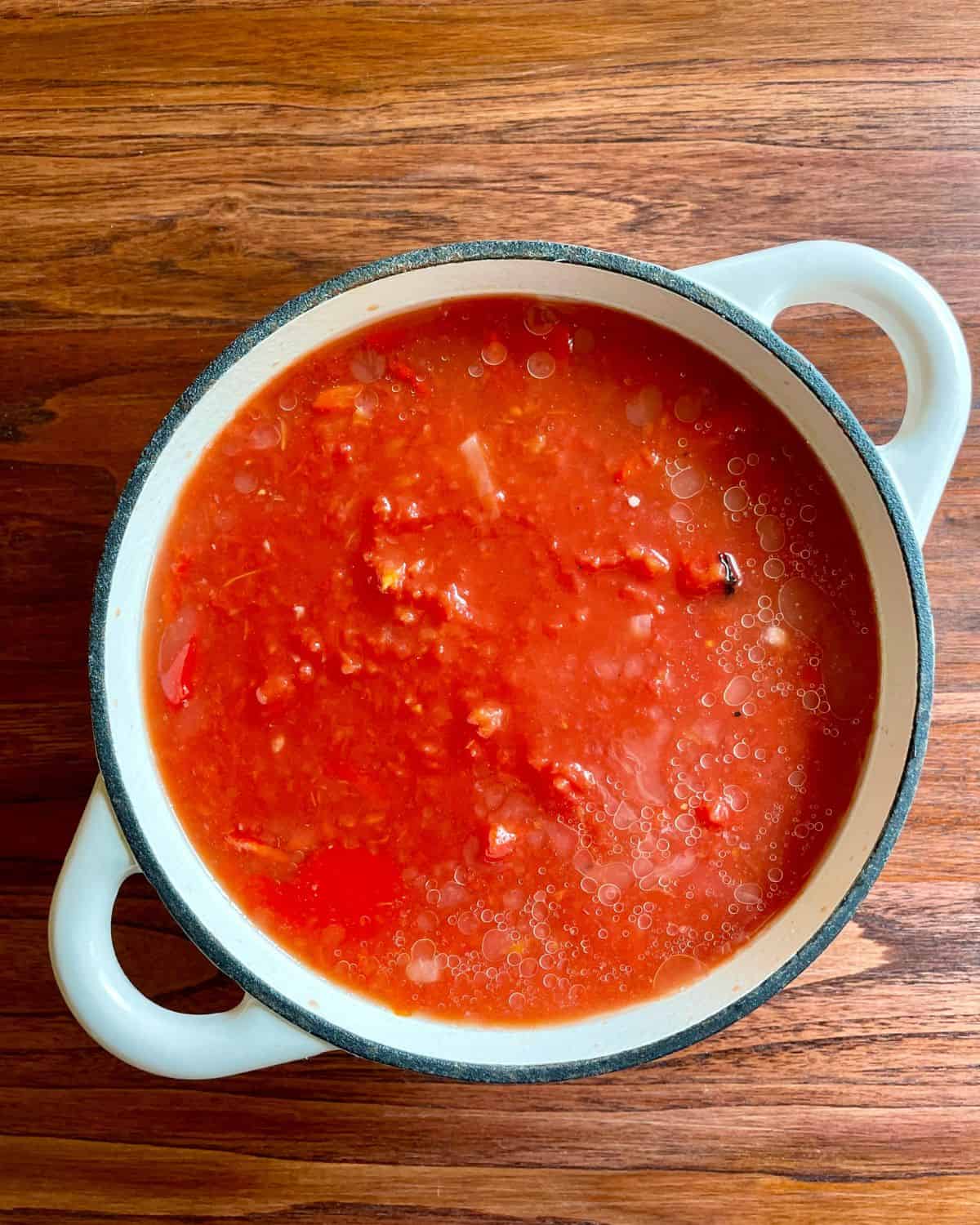 Stewed tomatoes and chicken broth added to the pot.