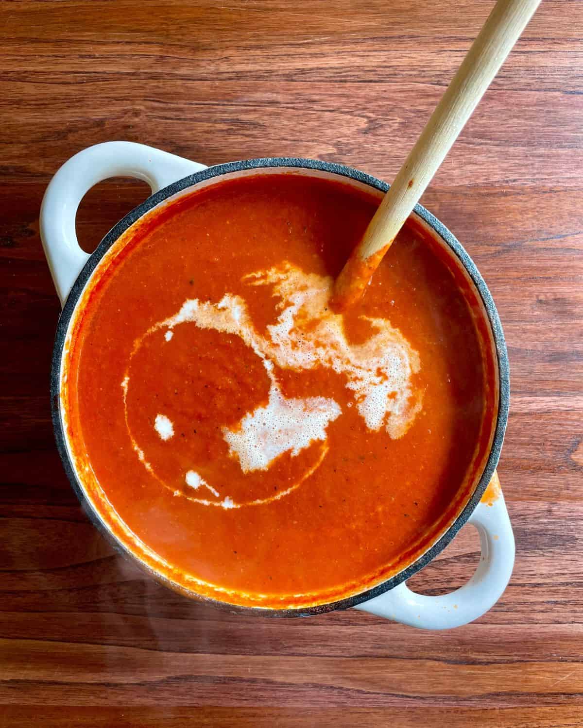 Heavy cream drizzled into the tomato and red pepper soup.