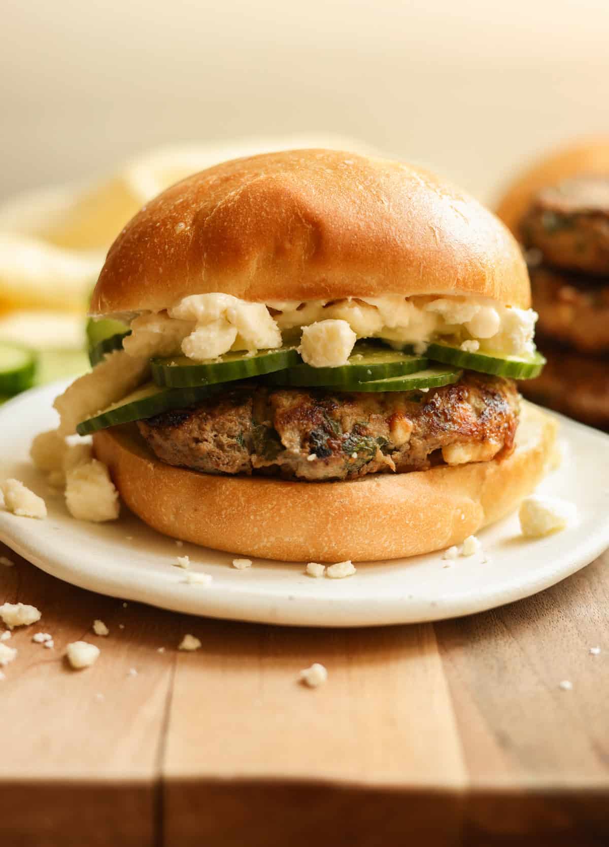 A spinach feta turkey burger on a bun, topped with cucumber and feta cheese.