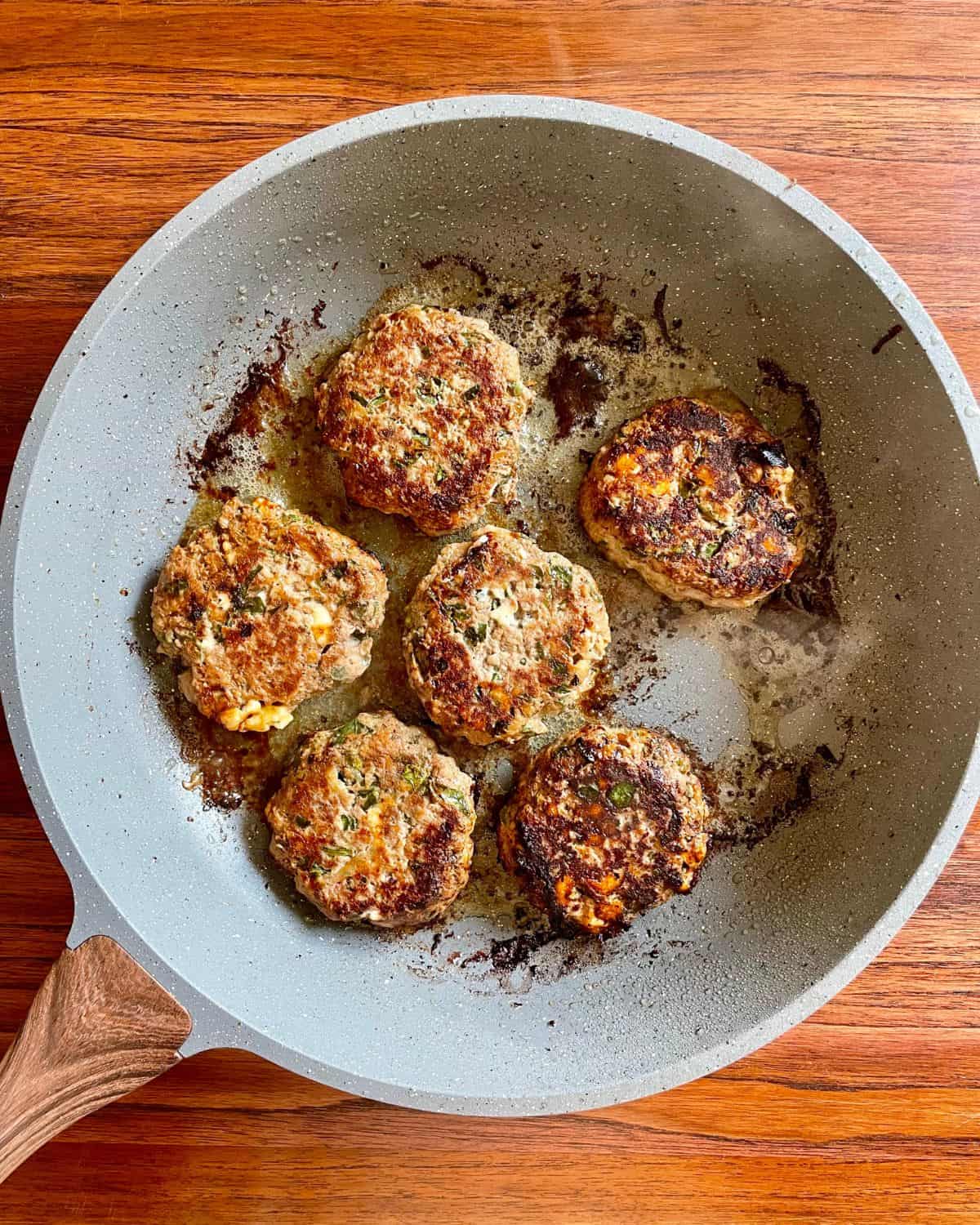 Cooked turkey burgers in a skillet.