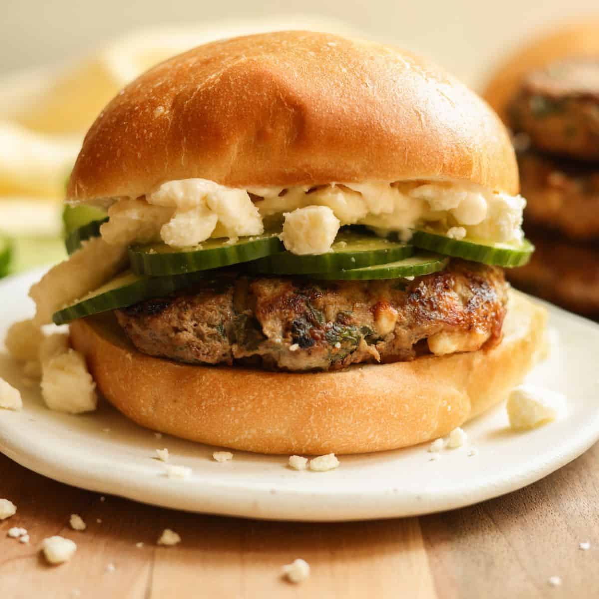 Feta and Spinach Turkey Burger on a bun topped with cucumber and feta cheese.