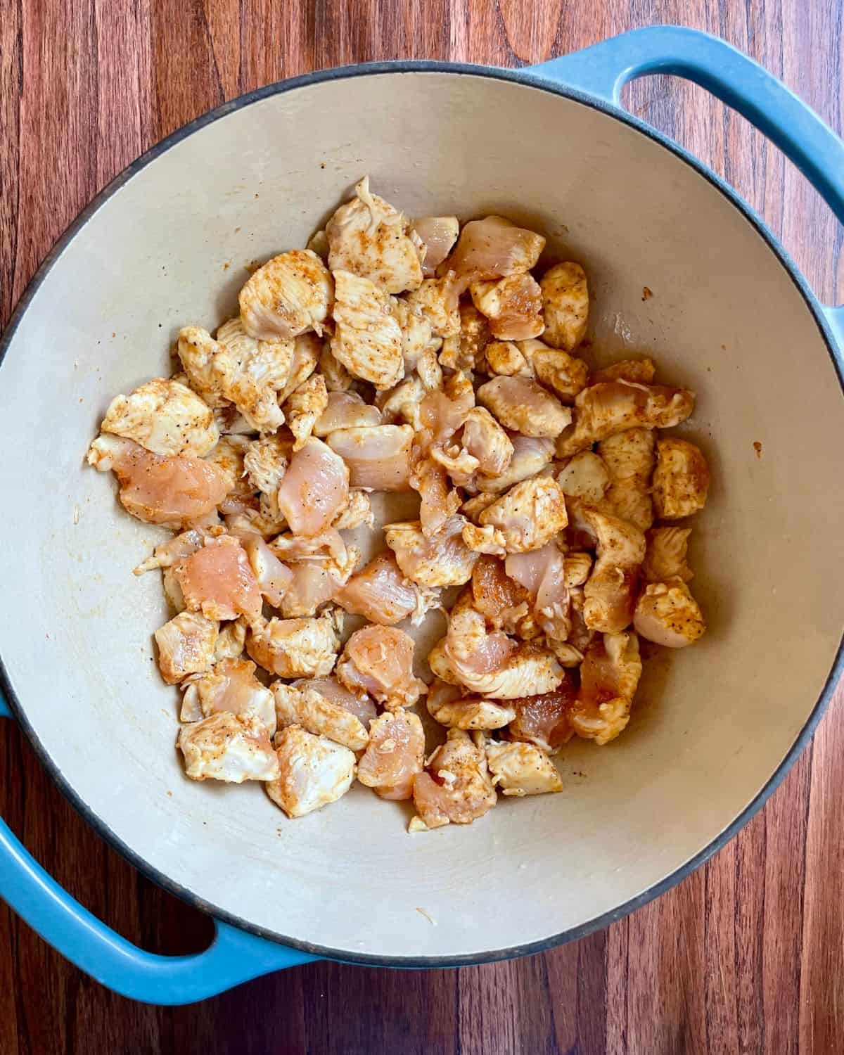 Chopped chicken breast cooking in a Dutch oven.